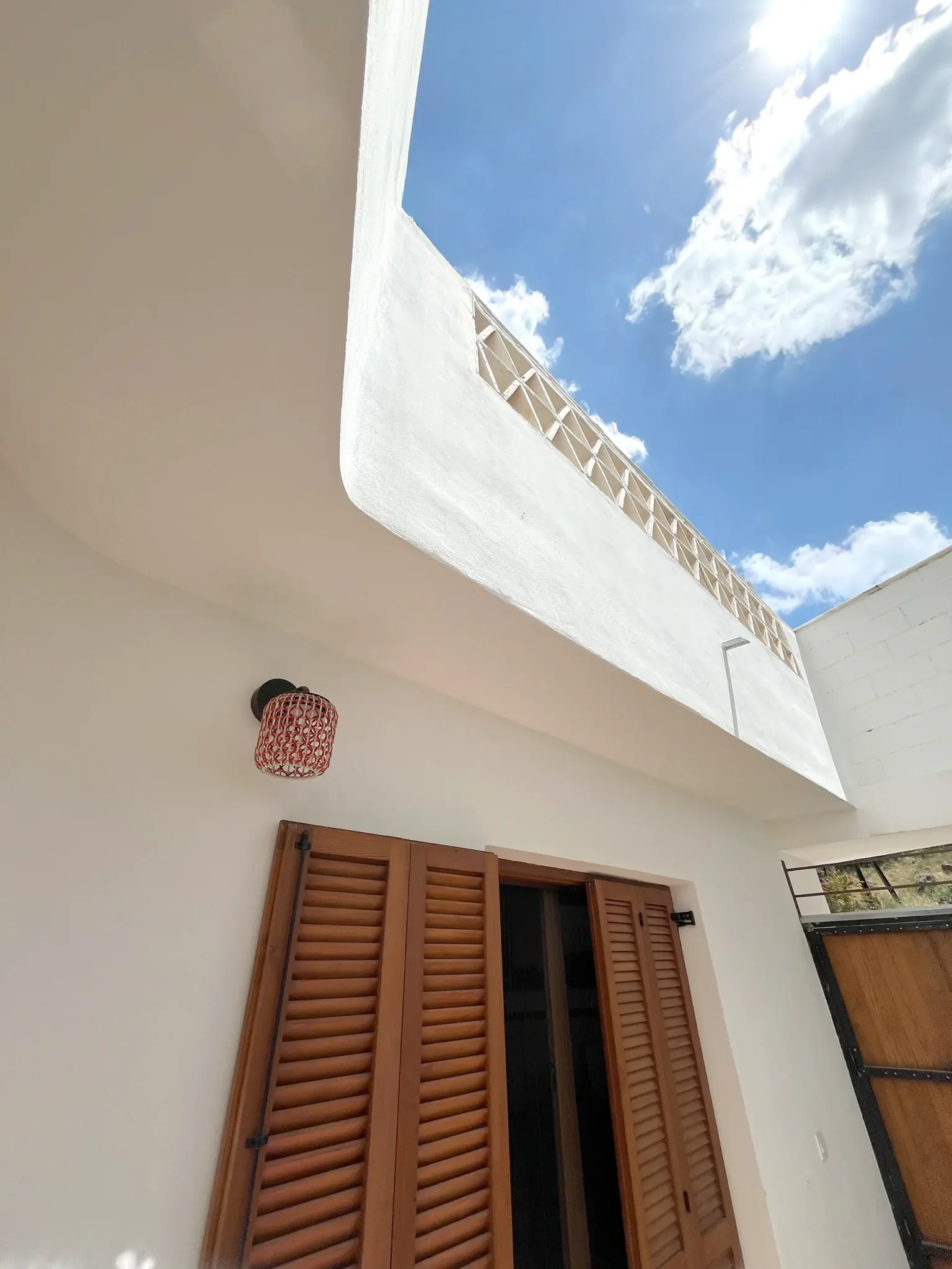 Muros encalados y contraventanas de madera vistos desde el patio de la casa cueva de la Bola de Oro